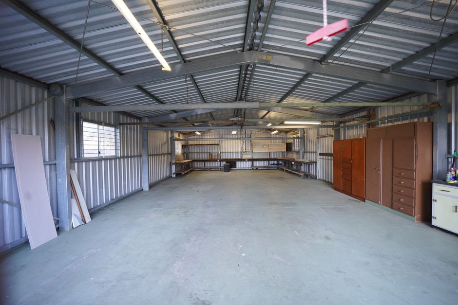 Empty industrial garage with metal walls and concrete floor ready for renovation or use.